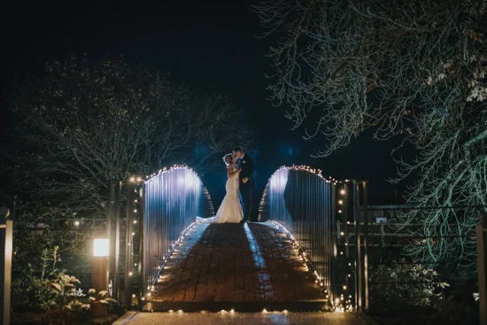 bride and groom stood on the moat bridge at night