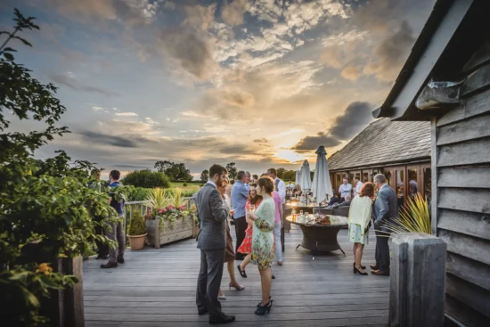 Guests enjoy a drinks reception on the terrace at Sandhole Oak Barn