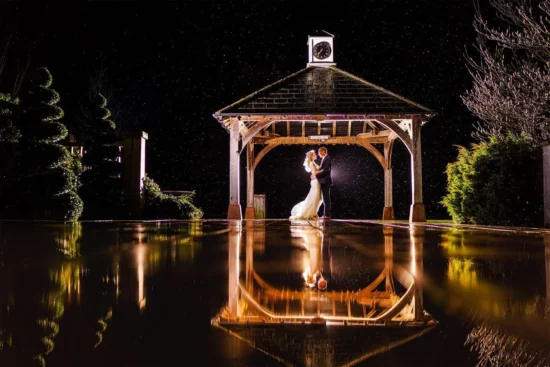 A couple embrace under the Clock Tower in the evening at Sandhole Oak Barn