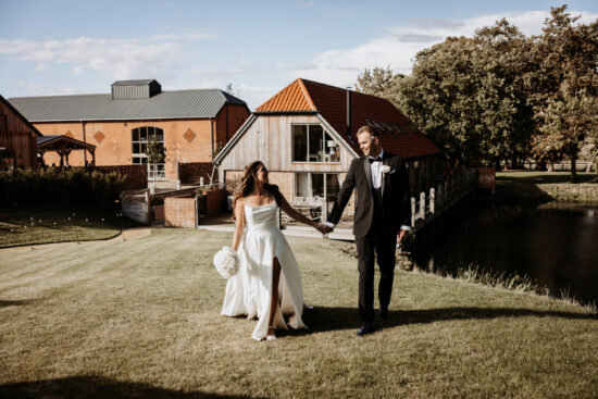 A bride and groom celebrate in the gardens at Branches Park wedding venue in Suffolk